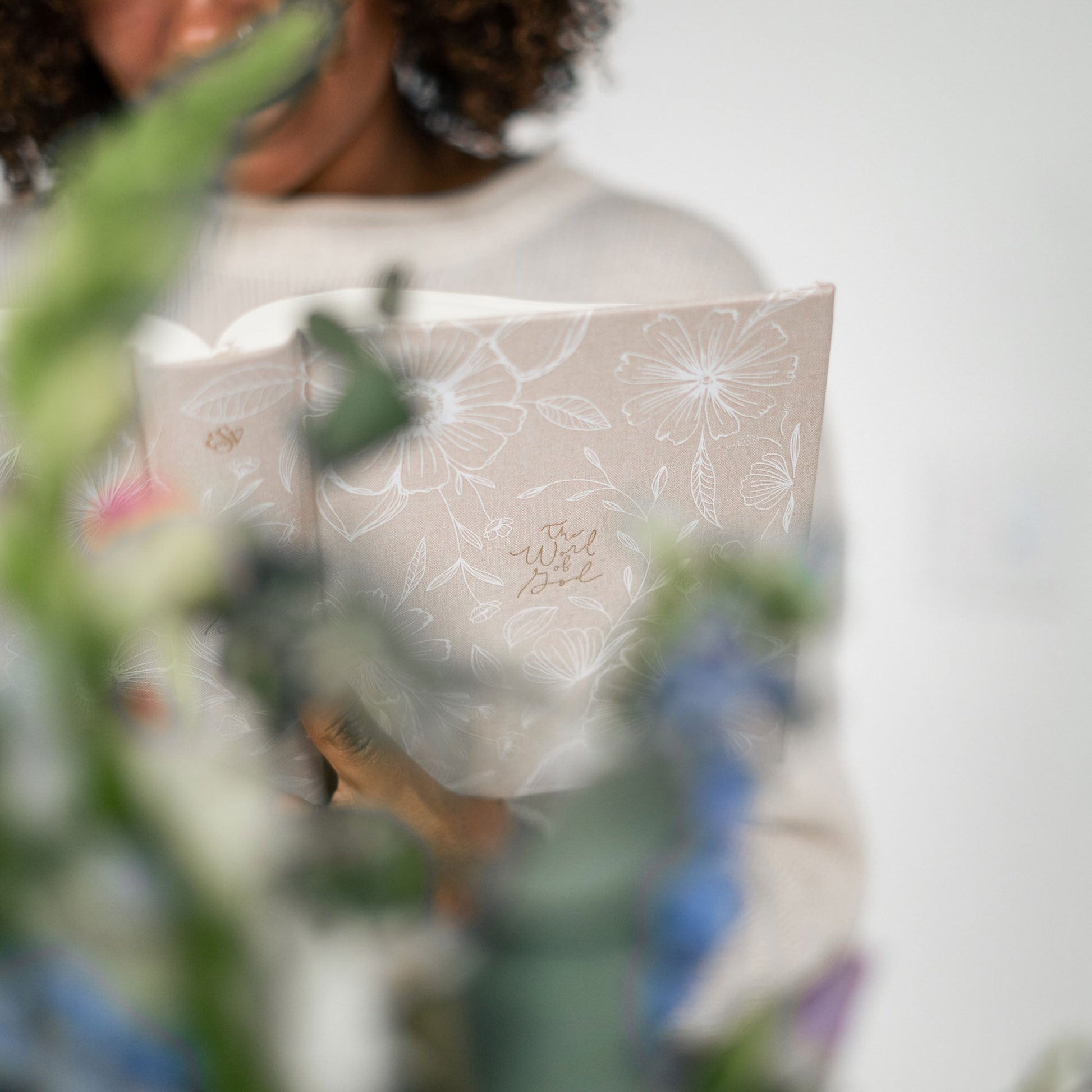 Aesthetic Bible Cover, beige linen with white flowers and gold foil lettering: woman holding Bible
