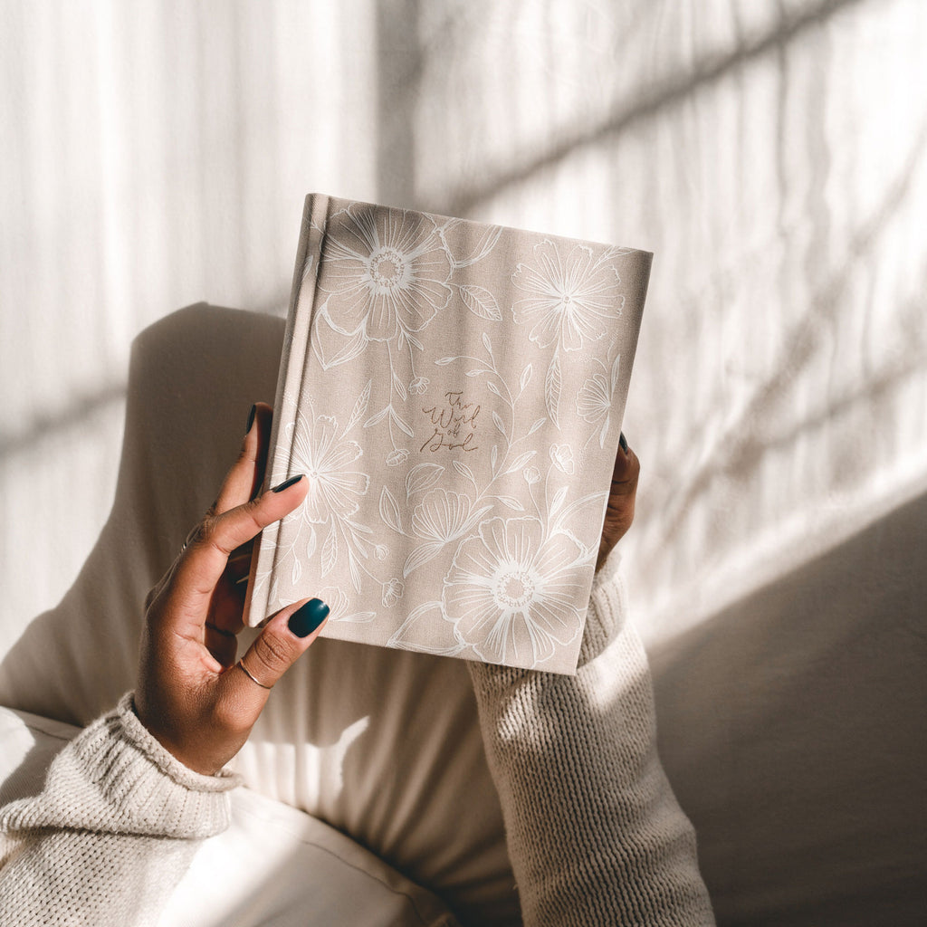 Woman holding Aesthetic Bible Cover, beige linen with white flowers and gold foil lettering: